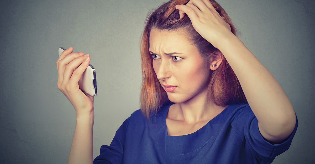 A lady using her phone to look at her trichotillomania