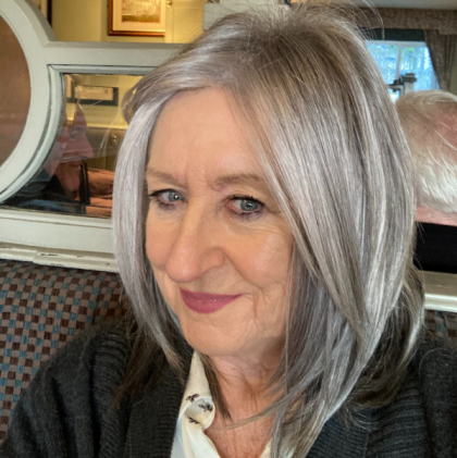 Woman wearing a salt and pepper grey wig by Noriko Rene of Paris.