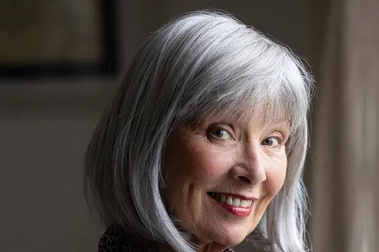 Smiling woman wearing the Petite Poppy wig by Natural Image in Medium Grey, a sleek silver bob with a full fringe