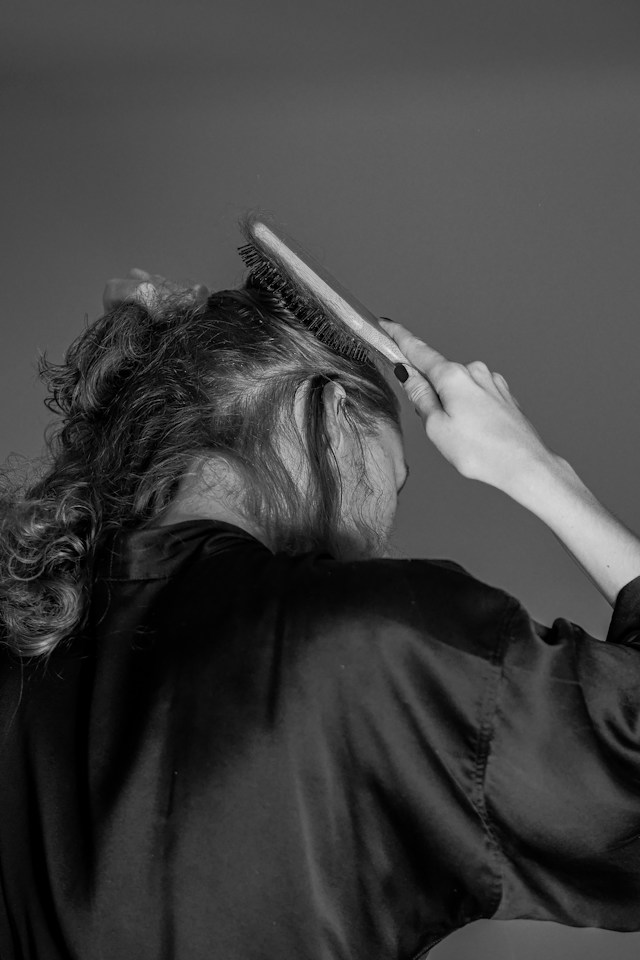 Woman brushing her hair and considering shaving her hair due to hair loss