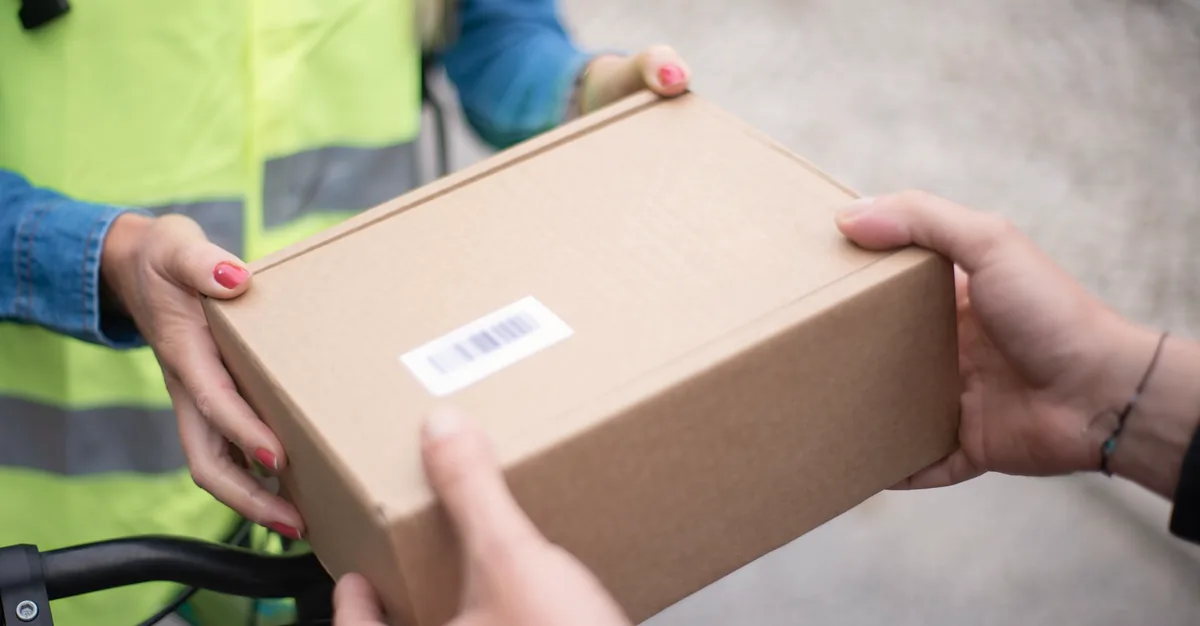 Courier handing over a plain brown parcel with no branding, only a barcode label